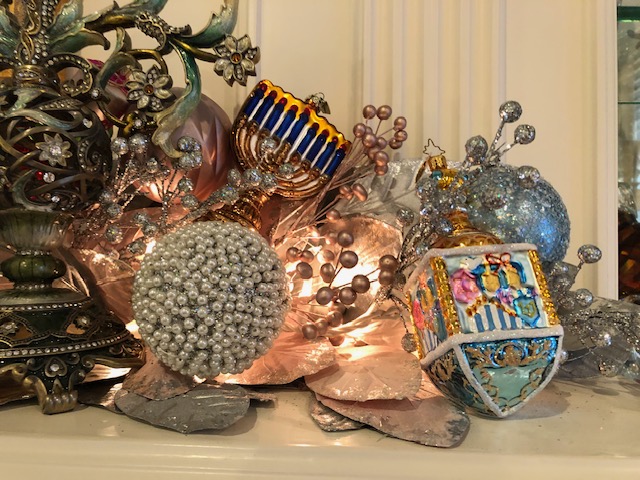 Ornate display with decorative spheres, a colorful menorah, and floral accents. Rich detailing emphasizes a festive, elegant ambiance with artistic craftsmanship.