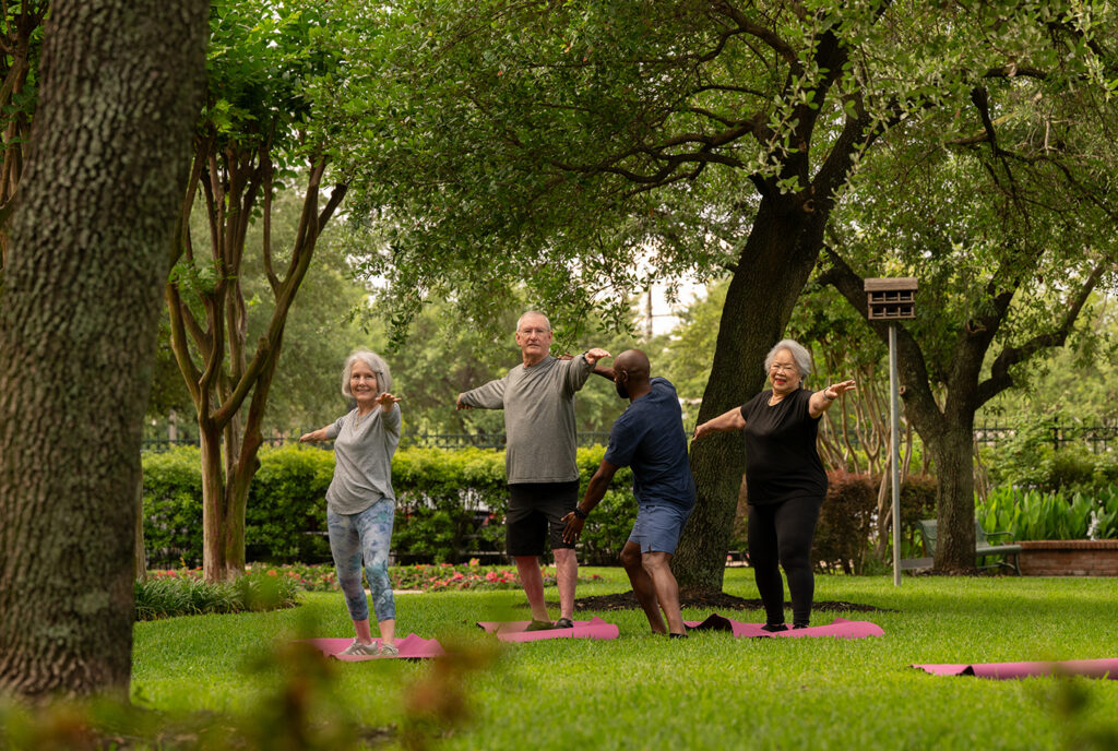 group of seniors doing yoga outdoors in a park