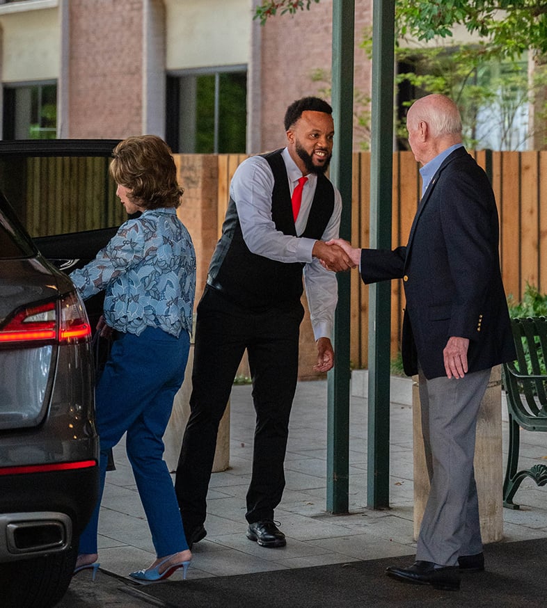 the Hallmark community usher holds the car door for a senior couple as they go out downtown