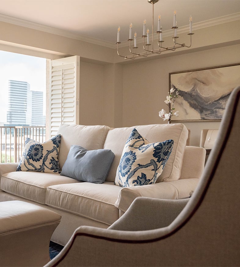 a photo of the interior of one of the senior apartments at The Hallmark complete with a window view of the city and furnished with couches.
